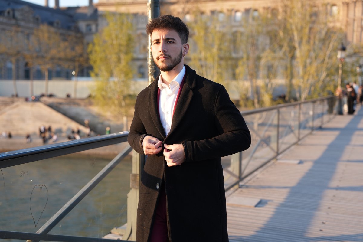 El Rayhan Loudhni sur un pont parisien avec le Musée du Louvre en arrière-plan